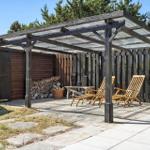 Terrasse mit Holzliegen und Pavillon unter blauem Himmel.