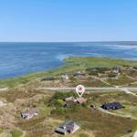 Aerial view of coastal property with houses on grassy terrain near water.