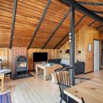 Wohnbereich mit Kamin, Sofa und Esstisch unter Holzdecke.