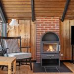 Wohnraum mit Kamin, Sessel und TV. Holzwände und Boden.