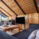 Wohnzimmer mit Sofa, Couchtisch und Fernseher unter Holzdecke.