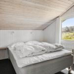 Schlafzimmer mit Doppelbett, Fenster und Holzdecke.