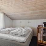 Schlafzimmer mit Bett, Kinderbett und Fenster. Holzdecke und weiße Wände.