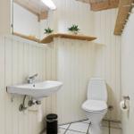 Badezimmer mit Toilette, Waschbecken und Spiegel an der Wand.