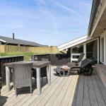 Terrasse mit Tisch, Stühlen und Liegen. Holzdecke, Fenster und Zaun sichtbar.