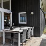 Terrasse mit Esstisch und Stühlen vor einem Haus mit dunkler Holzfassade.