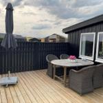 Terrasse mit Tisch, Stühlen und Sonnenschirm neben einem Haus