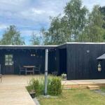 Schwarzer Holzausbau mit Terrasse, Tisch, Stühlen und Pflanzen im Garten.