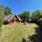 Rotes Haus mit Garten und Terrasse unter blauem Himmel