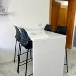 Weißer Esstisch mit schwarzen Barhockern und Marmorfliesenboden.