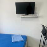 Schlafzimmer mit blauer Matratze, Wand-TV und Stühlen.