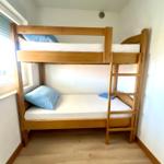 Zimmer mit Holzbett, zwei Matratzen und blauen Kissen.