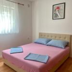 Schlafzimmer mit Bett, Vorhängen und Wandbild.