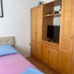 Schlafzimmer mit Bett, Holzschrank und Fernseher