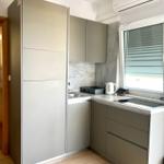 Küche mit grauen Schränken, Arbeitsplatte und Fenster mit Jalousie.