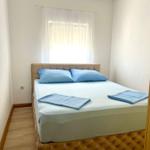 Schlafzimmer mit Bett, blauen Kissen und Vorhängen an Fenster