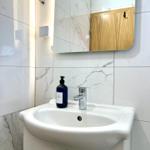 Waschbecken mit Spiegel und Seifenspender an marbliertem Wandverkleidung.