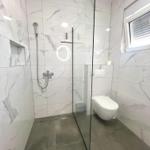 Badezimmer mit Dusche, Toilette und Fenster