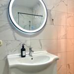 Badezimmer mit Waschbecken, Spiegel und Dusche