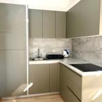 Küche mit grauen Schränken, Marmorwand und Holzboden