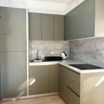 Küche mit grauen Schränken, Marmorwand und Edelstahlspüle.