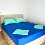 Schlafzimmer mit Bett, blauer Bettwäsche und hellgrünen Kissen.