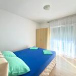 Schlafzimmer mit Bett, Kleiderschrank und Fenster mit Vorhängen.