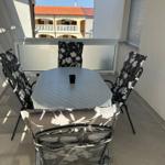 Terrasse mit Tisch und vier Stühlen mit floralen Bezügen.