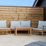 Terrasse mit Holzgeländer, Sitzgruppe und Tisch.