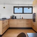 Moderne Küche mit Holzschränken, Arbeitsplatte und Fenster.