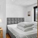 Schlafzimmer mit Bett, Nachttisch und Fensterblick.