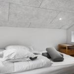 Schlafzimmer mit Bett, Nachttisch und Fenster. Decke aus Steinplatten.