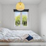 Bedroom with bed, window, and ceiling lamp.