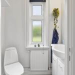 Bathroom with toilet, sink, and window with plants.