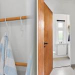 Bathroom with shower, toilet, and window. Wooden towel rack with towel.