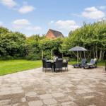 Terrace with table, chairs, and loungers under umbrella.