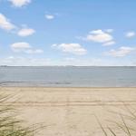 Beach with sand and water under blue sky with white clouds.