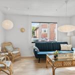 Living room with blue sofa, rattan chairs, and glass table. Window shows exterior view.