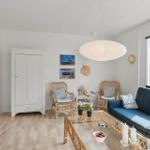 Living room with blue sofa, two rattan chairs, and glass table.