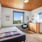 Schlafzimmer mit Bett, Fenster, Schrank und Stuhl.