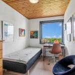 Schlafzimmer mit Bett, Schreibtisch und Stuhl. Holzdecke und Fenster mit Blick.