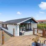 Modernes Ferienhaus mit großem Holzterrasse und Gartenbereich.