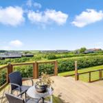 Terrasse mit Sitzgelegenheit und Blick auf grüne Landschaft und Häuser.