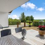 Terrasse mit Tisch, Stühlen und Blick auf grüne Landschaft.