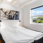 Schlafzimmer mit Doppelbett, Fenster und Wandbild.