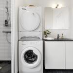 Waschmaschine und Trockner stehen in einem Badezimmer mit Dusche und Waschbecken.