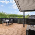 Terrasse mit Tischen, Stühlen und Grill. Blick auf Grünflächen und Nachbarhäuser.