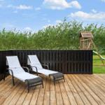 Terrasse mit zwei Liegestühlen, Holzdecke und Spielhaus im Hintergrund.