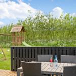 Terrasse mit Tisch und Stühlen, Spielplatz im Hintergrund, grünes Gras und Bäume.