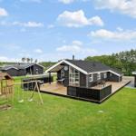 Schwarze Holzhütte mit großem Balkon und Spielplatz auf grünem Grundstück.
